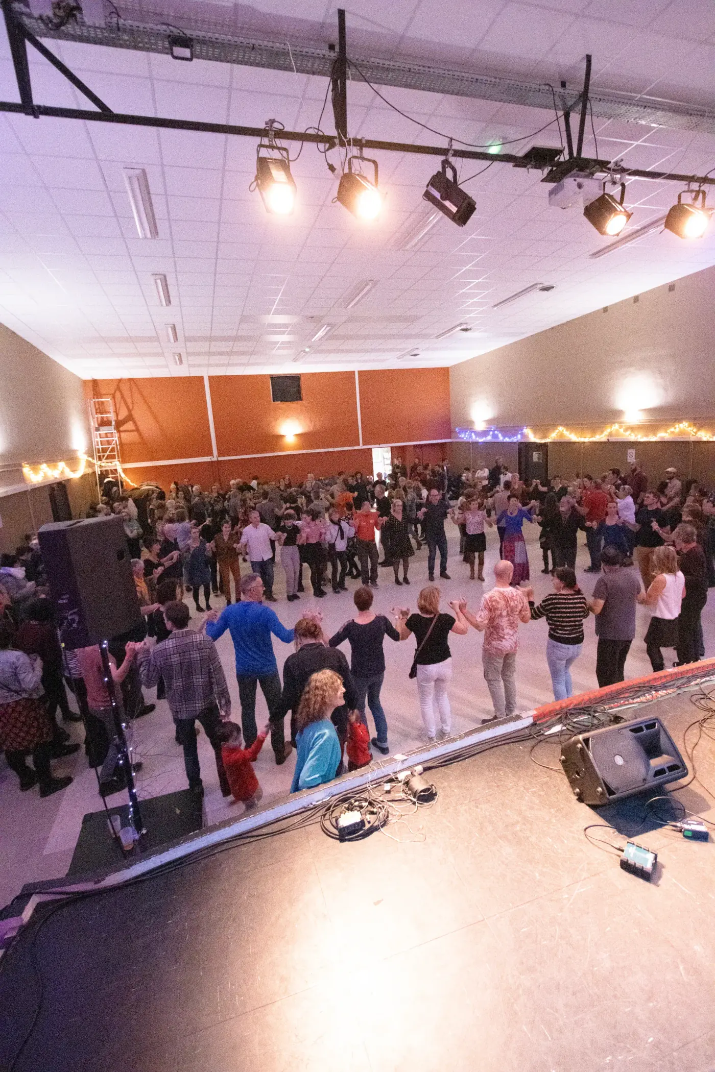 Danseurs en cercle sous les guirlandes de la salle